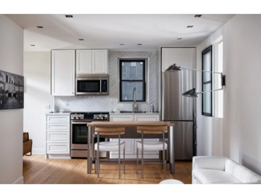 ADU studio design rendering with white kitchen cabinets and a dining table.