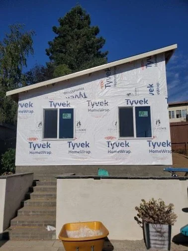 ADU exterior during construction with housewrap and entry steps.