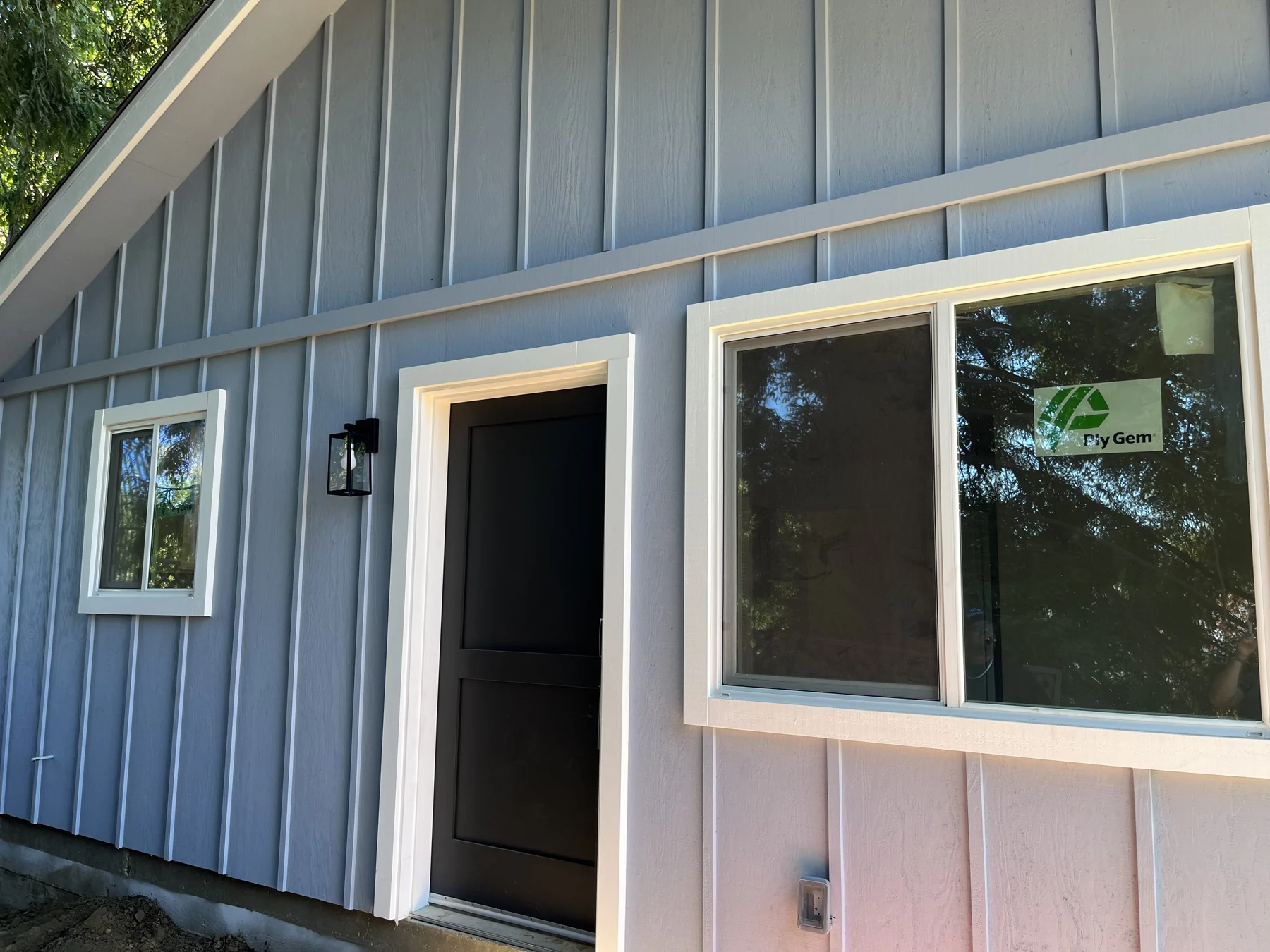 Blue-gray ADU siding, white-trimmed windows and entry doorway.