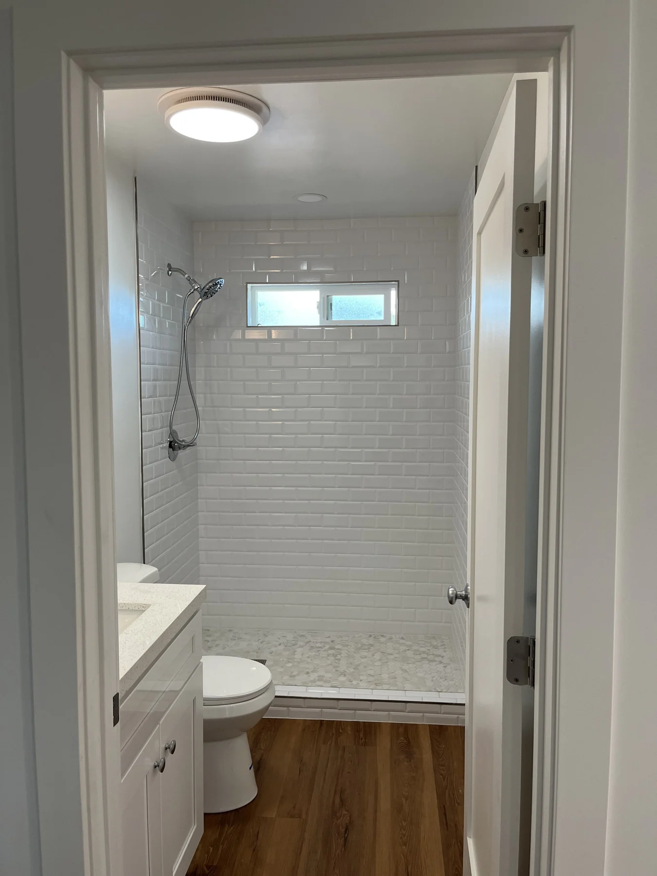 ADU bathroom with a tiled tub surround and white fixtures.