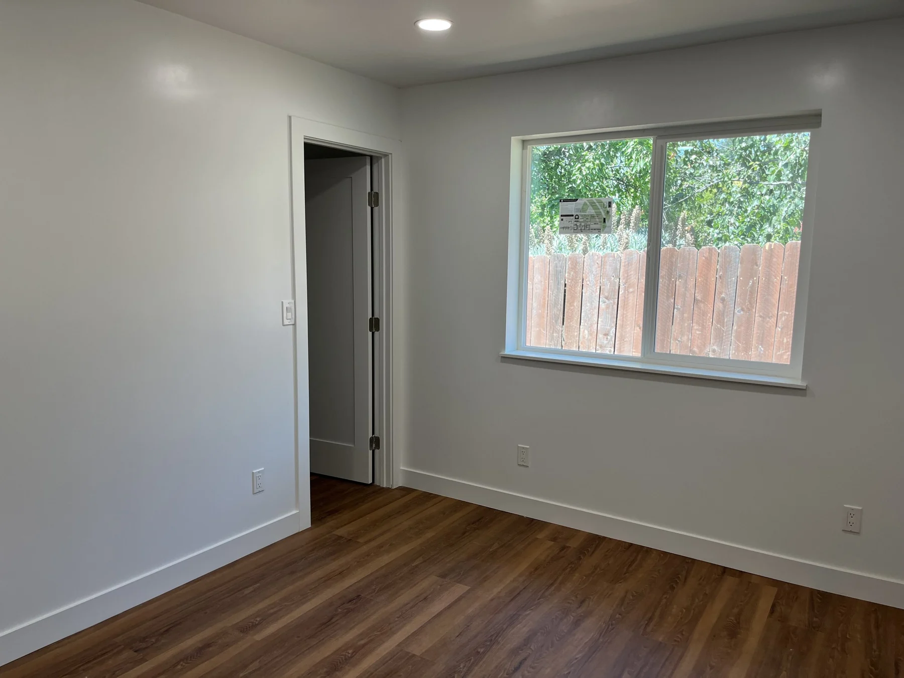 ADU room with recessed lights, white walls and a large window.