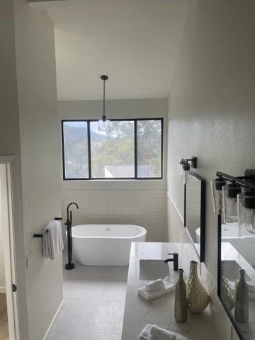 Bathroom with a freestanding bathtub and large window.