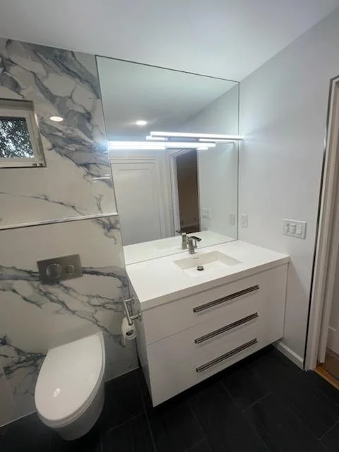 Bathroom with marble-pattern wall tile and a white floating vanity.