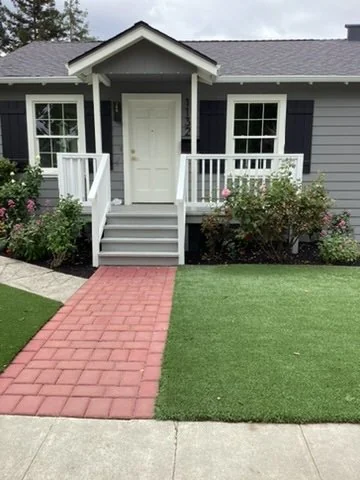 Gray house exterior with white trim, front porch and brick walkway.