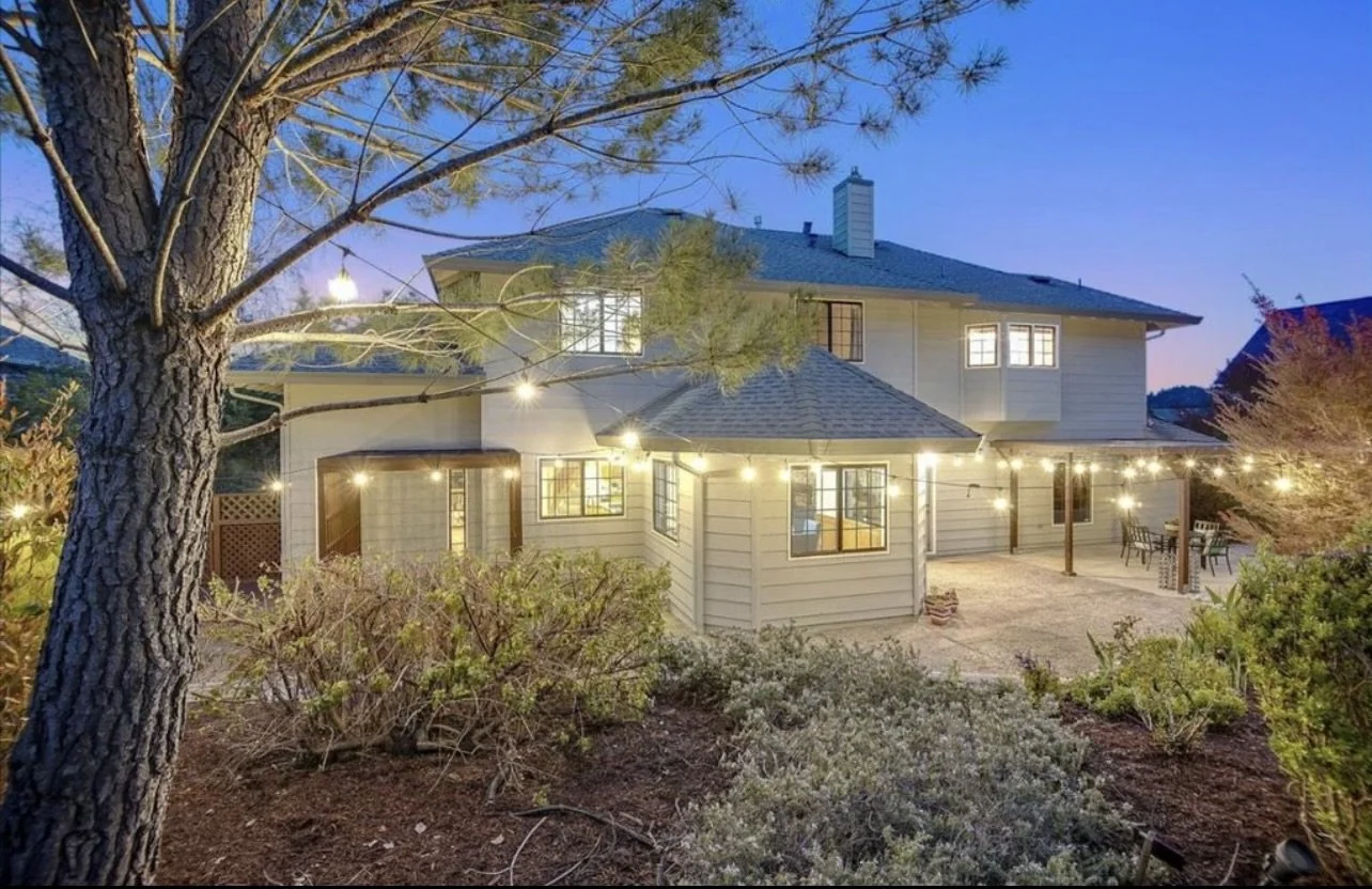 Two-story painted house and landscaped garden at dusk.
