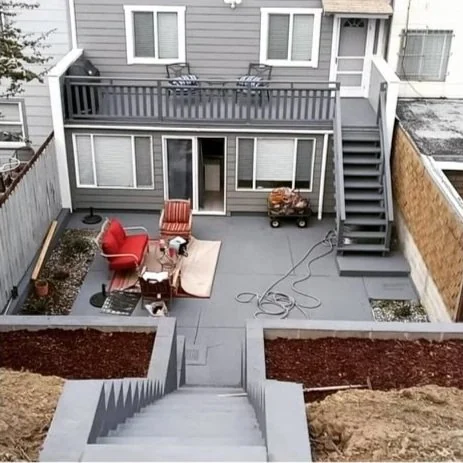 Gray house exterior with painted decks, stairs and a courtyard.