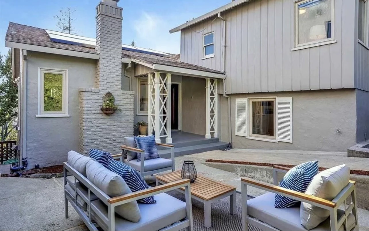 Painted house exterior and furnished backyard patio.