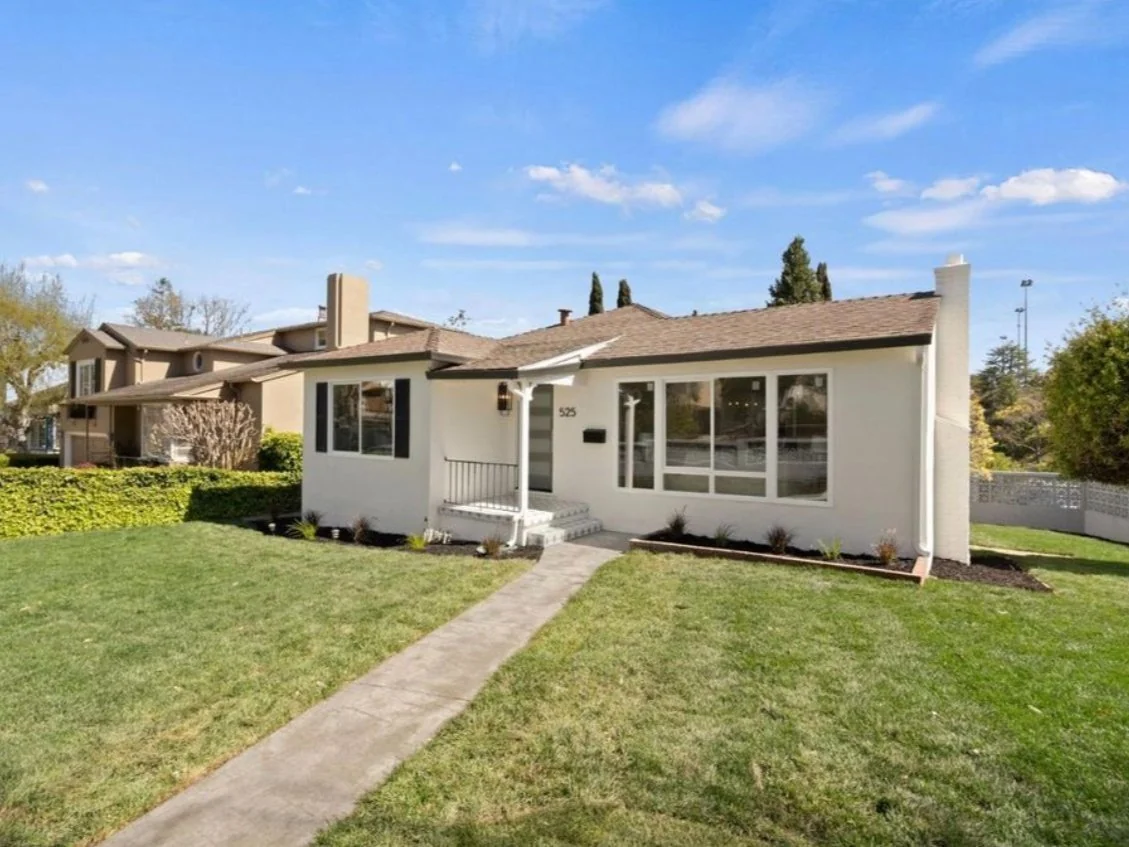 White painted house exterior with a lawn, walkway and broad windows.