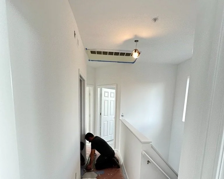 White interior hallway during painting and ceiling work.