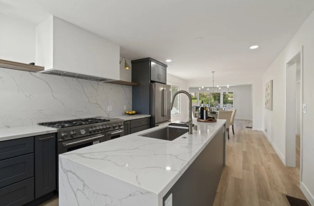 Modern kitchen with a marble island and charcoal cabinetry.