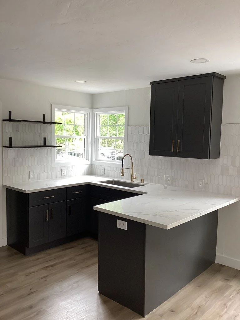 Compact kitchen with dark cabinetry and white countertops.