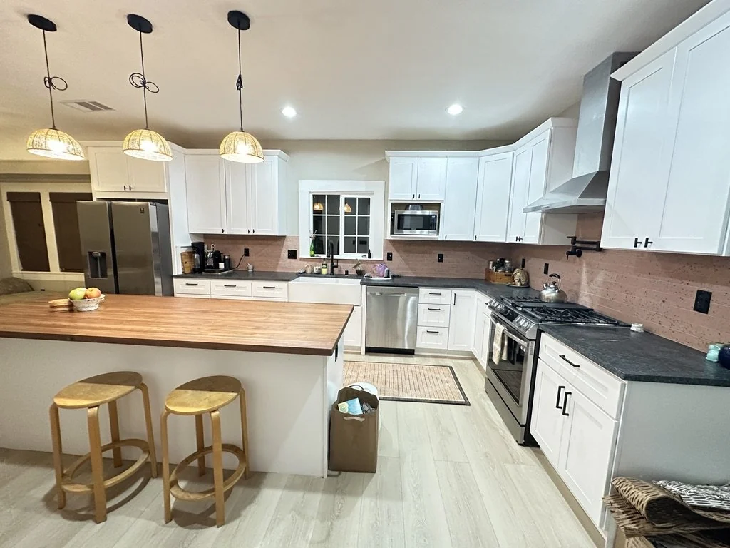 White kitchen with a wood-topped island and pendant lights.
